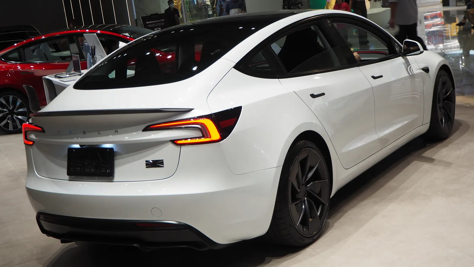 White Tesla Model 3 Performance sedan, rear three-quarter view at an indoor display