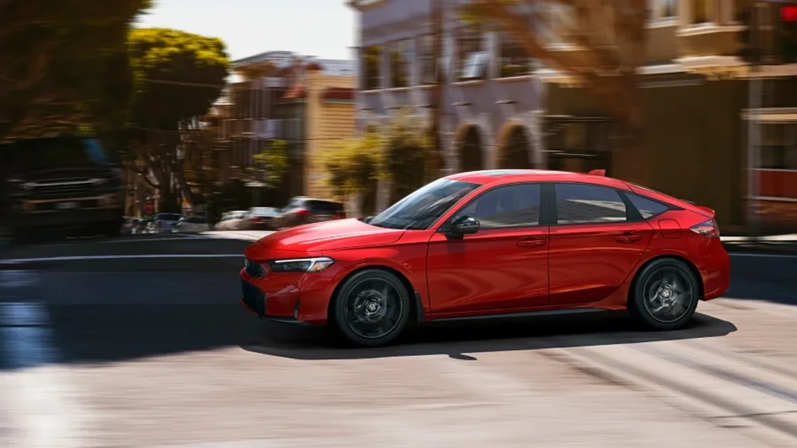 2026 Honda Civic Hatchback in red driving on a city street, Canadian model